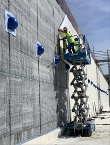 Two men on lift applying AVM product to wall