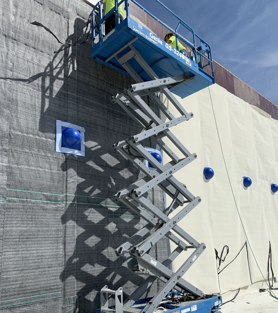 Two men on fork lift installing Aussie Clay Dual Layer Installation 